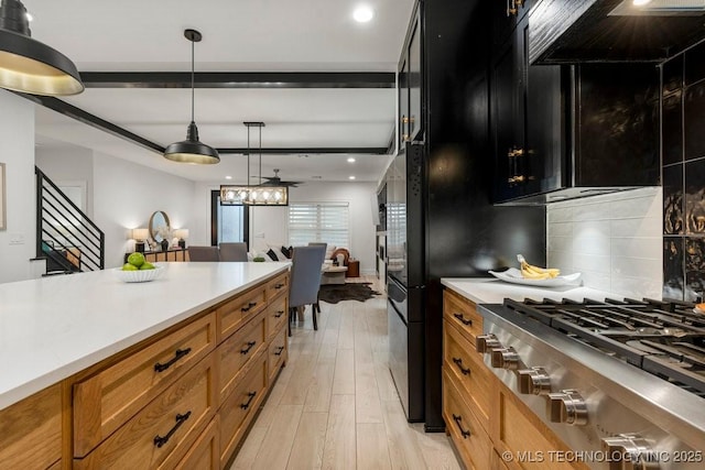 kitchen featuring light wood-type flooring, backsplash, custom range hood, stainless steel gas cooktop, and hanging light fixtures