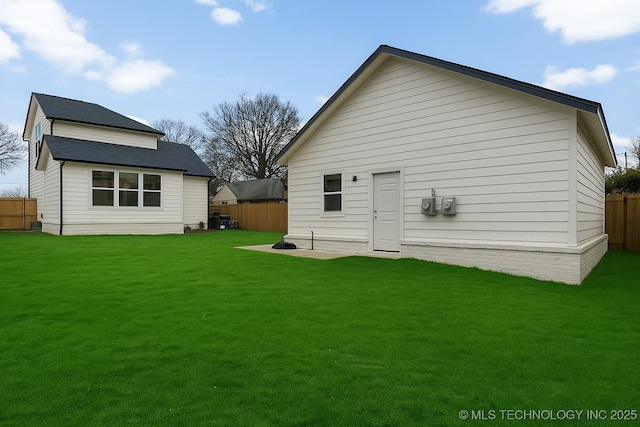 rear view of property with fence and a lawn