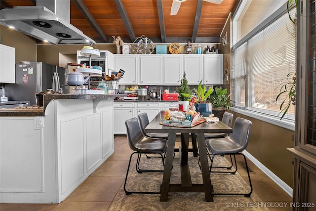 kitchen featuring white cabinets, tile patterned flooring, extractor fan, and stainless steel refrigerator