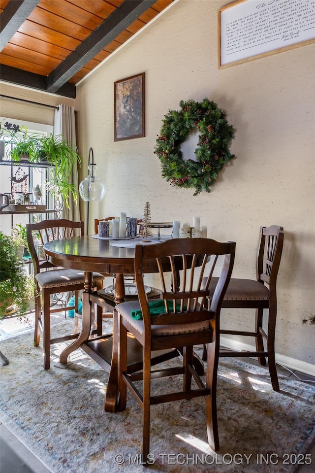 dining space featuring lofted ceiling with beams and wooden ceiling