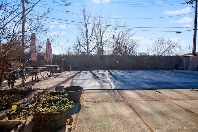 view of swimming pool featuring a patio area and a storage shed