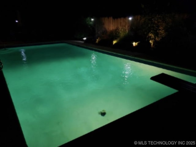 pool at night featuring a diving board