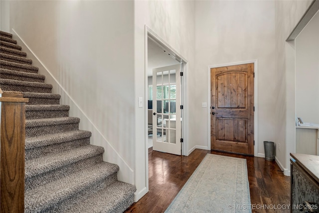 foyer entrance with dark wood-type flooring and a high ceiling