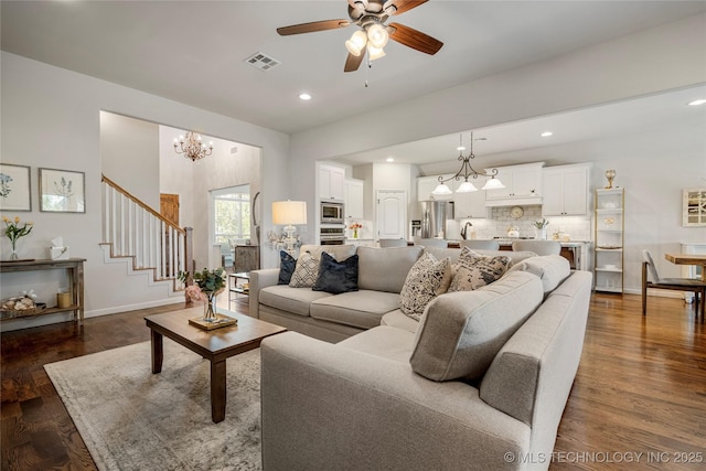 living room featuring dark hardwood / wood-style flooring and ceiling fan with notable chandelier