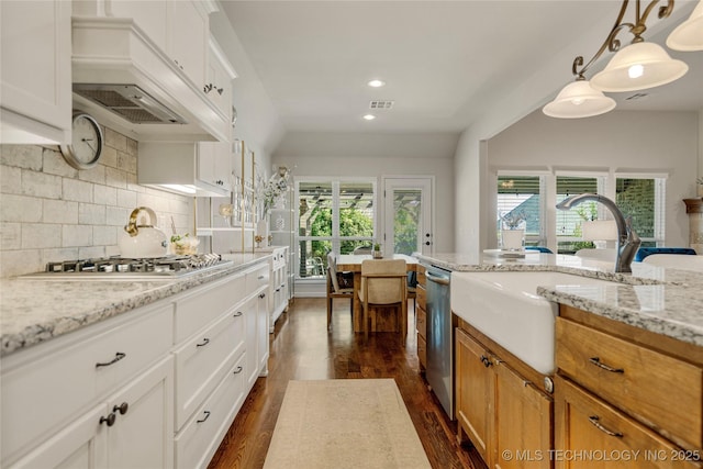 kitchen with appliances with stainless steel finishes, tasteful backsplash, light stone counters, pendant lighting, and white cabinets