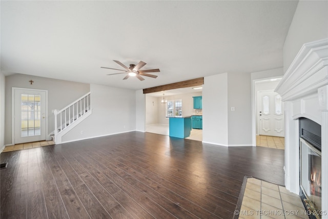 unfurnished living room featuring ceiling fan, light hardwood / wood-style flooring, beamed ceiling, and plenty of natural light