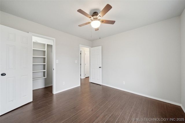 unfurnished bedroom featuring ceiling fan, dark hardwood / wood-style flooring, a walk in closet, and a closet