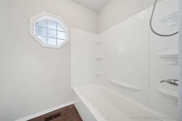 bathroom with hardwood / wood-style flooring and shower / washtub combination