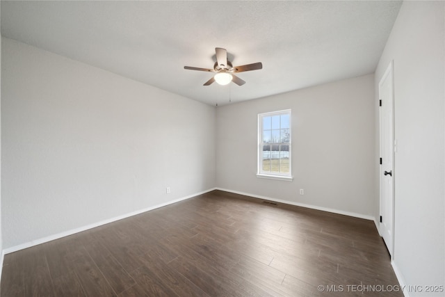 empty room with ceiling fan and dark hardwood / wood-style flooring