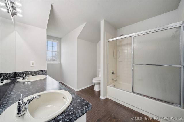 full bathroom featuring hardwood / wood-style floors, vanity, toilet, and shower / bath combination with glass door