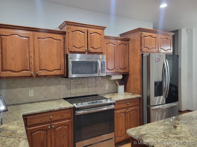 kitchen featuring appliances with stainless steel finishes, backsplash, and light stone counters