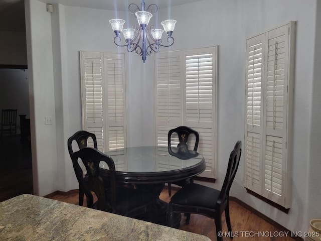 dining area with an inviting chandelier and dark wood-type flooring