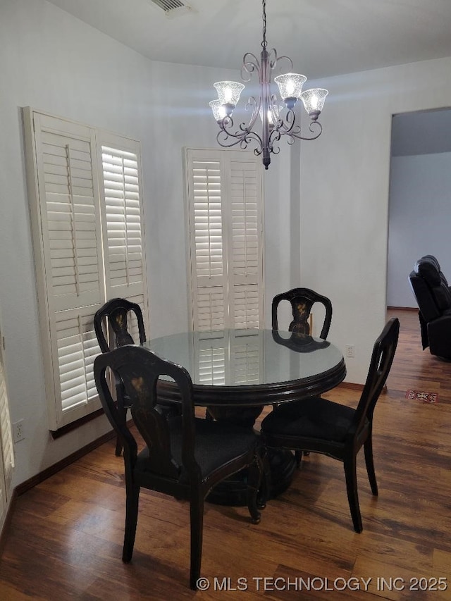 dining room with dark hardwood / wood-style floors and a notable chandelier