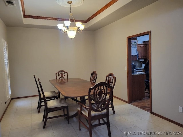 dining area featuring a chandelier, a tray ceiling, and ornamental molding