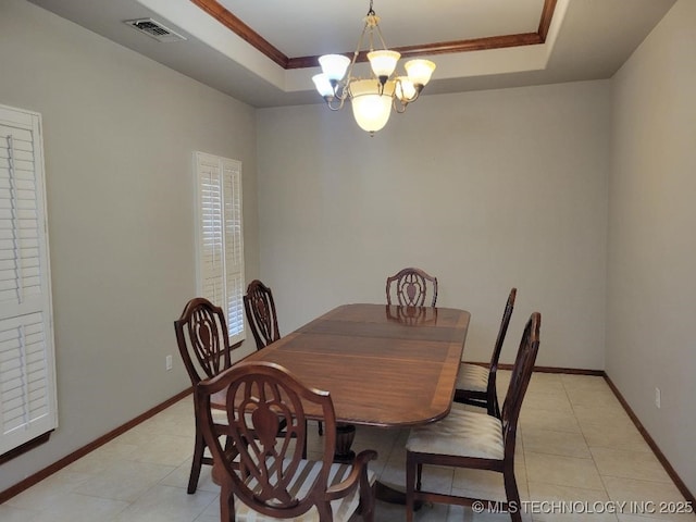 tiled dining space with a tray ceiling, ornamental molding, and an inviting chandelier