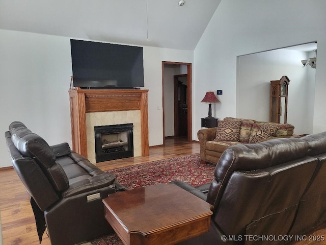 living room with a tile fireplace, wood-type flooring, and lofted ceiling