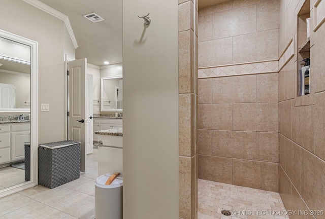 bathroom featuring tile patterned floors, vanity, a tile shower, and crown molding