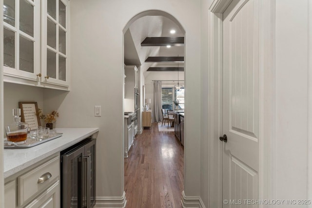 bar featuring light stone countertops, dark hardwood / wood-style flooring, beamed ceiling, white cabinets, and wine cooler