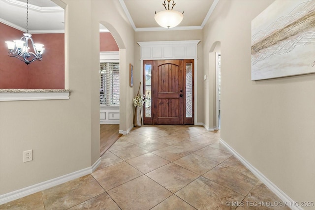 tiled entryway with a chandelier and ornamental molding