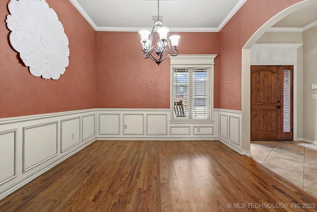 unfurnished dining area featuring crown molding, an inviting chandelier, and hardwood / wood-style flooring