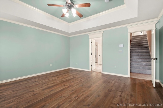 empty room with a raised ceiling, crown molding, and ceiling fan