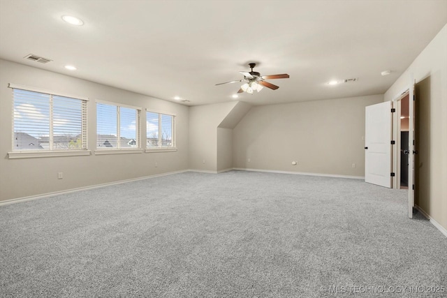 additional living space with ceiling fan and light colored carpet