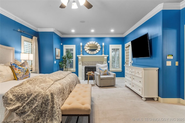 bedroom featuring a premium fireplace, ceiling fan, crown molding, and light colored carpet