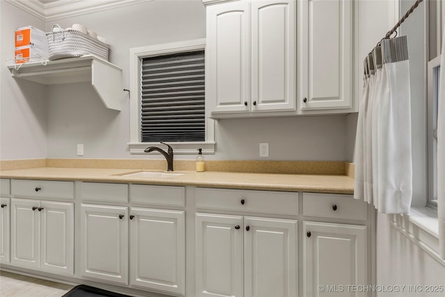 kitchen with white cabinets, crown molding, and sink