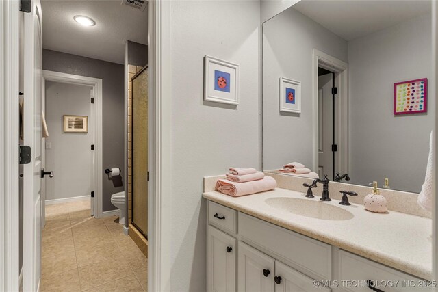 bathroom featuring tile patterned flooring, vanity, toilet, and an enclosed shower