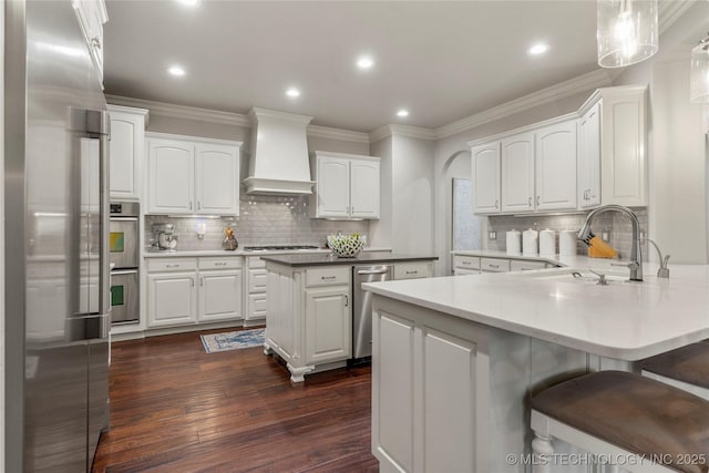 kitchen with premium range hood, backsplash, white cabinetry, and appliances with stainless steel finishes