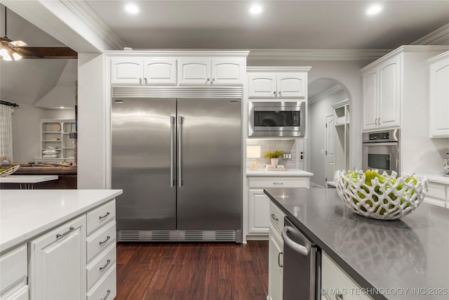 kitchen with dark hardwood / wood-style flooring, backsplash, ceiling fan, built in appliances, and white cabinetry