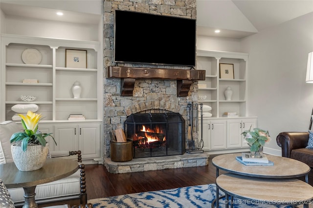 living room featuring a fireplace, built in shelves, dark hardwood / wood-style floors, and vaulted ceiling