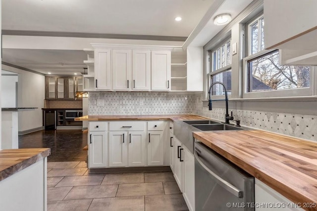 kitchen with stainless steel dishwasher, white cabinetry, butcher block counters, and sink