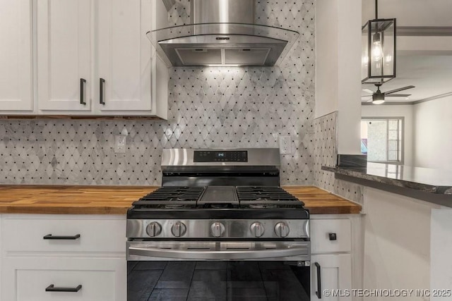 kitchen with white cabinetry, wall chimney range hood, stainless steel range with gas cooktop, butcher block countertops, and decorative light fixtures