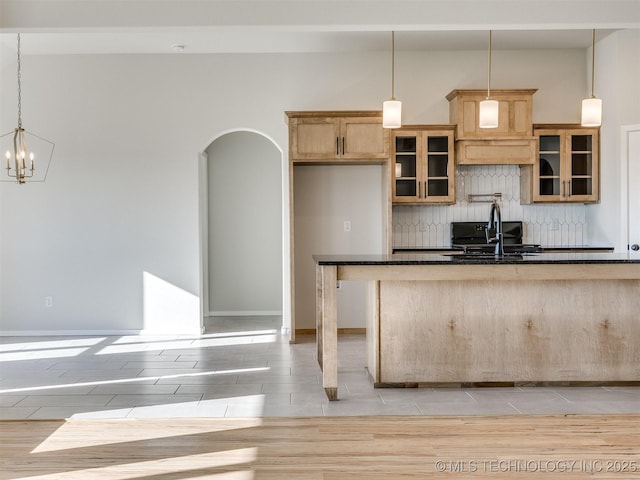 kitchen with tasteful backsplash, sink, decorative light fixtures, an inviting chandelier, and light tile patterned flooring