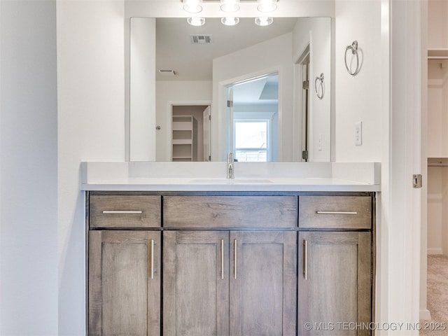bathroom featuring a spacious closet, visible vents, and vanity