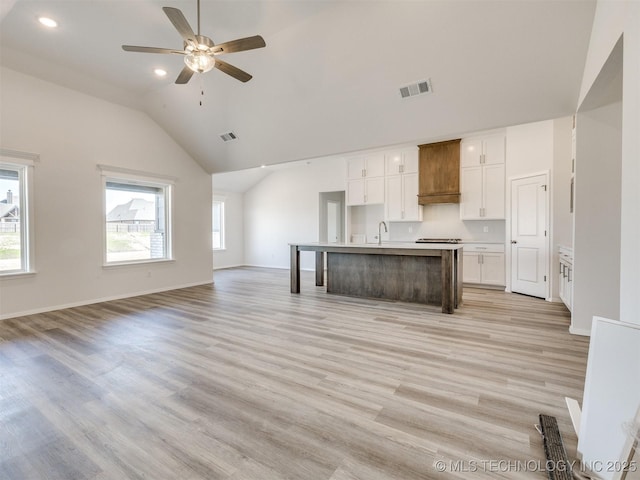 kitchen featuring vaulted ceiling, open floor plan, a sink, and visible vents
