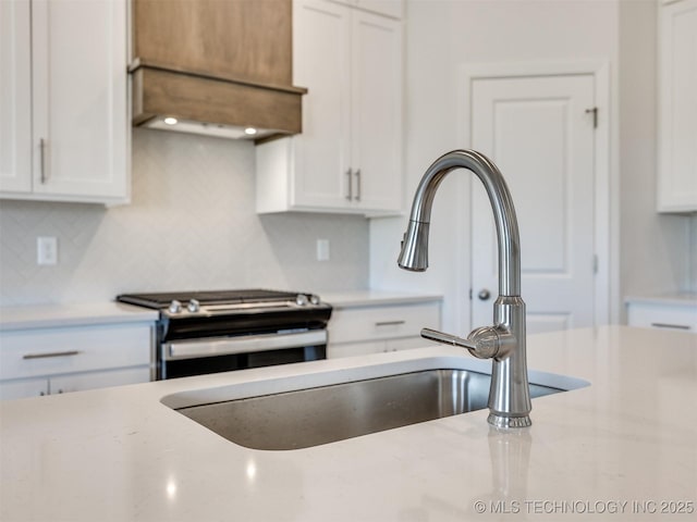 kitchen with white cabinets, tasteful backsplash, electric stove, and a sink