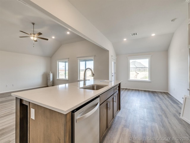 kitchen featuring lofted ceiling, open floor plan, stainless steel dishwasher, and a sink
