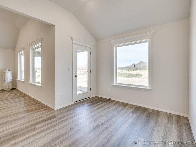interior space featuring vaulted ceiling, wood finished floors, and baseboards
