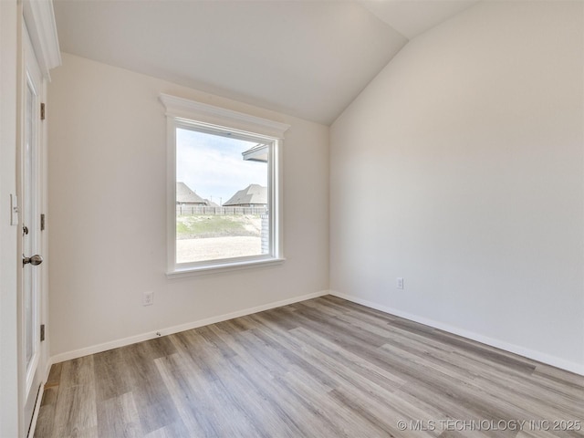 unfurnished room featuring lofted ceiling, baseboards, and wood finished floors