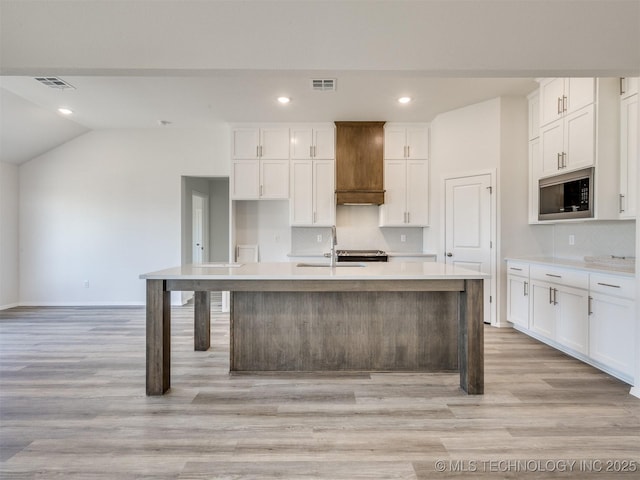 kitchen with visible vents, tasteful backsplash, built in microwave, and light wood-style flooring