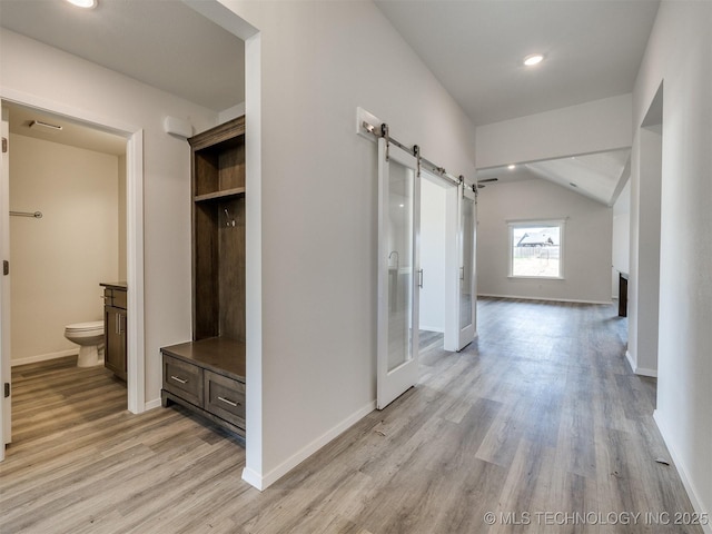 hall with a barn door, vaulted ceiling, light wood-style flooring, baseboards, and recessed lighting