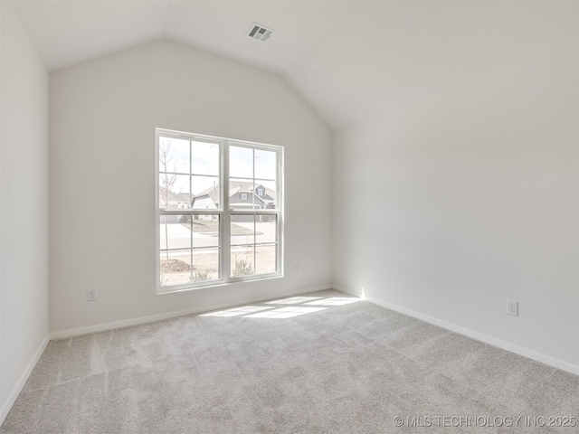 carpeted spare room featuring baseboards, vaulted ceiling, and visible vents