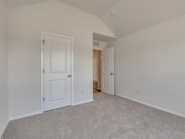 unfurnished bedroom with carpet, visible vents, lofted ceiling, and baseboards