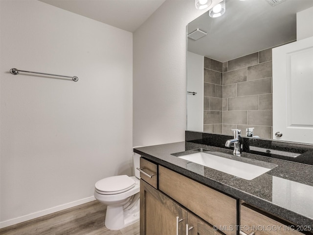 bathroom featuring toilet, vanity, wood finished floors, and baseboards