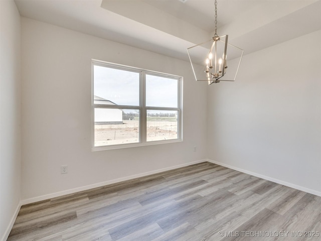 spare room with light wood-style flooring, baseboards, and a notable chandelier