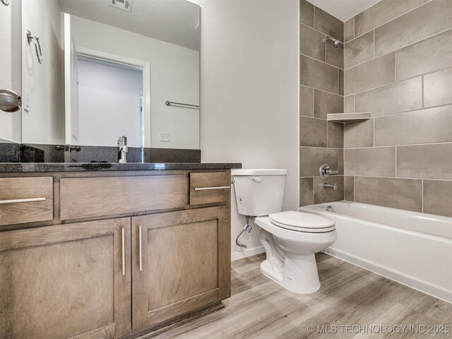 full bathroom featuring wood finished floors, vanity, toilet, visible vents, and bathing tub / shower combination