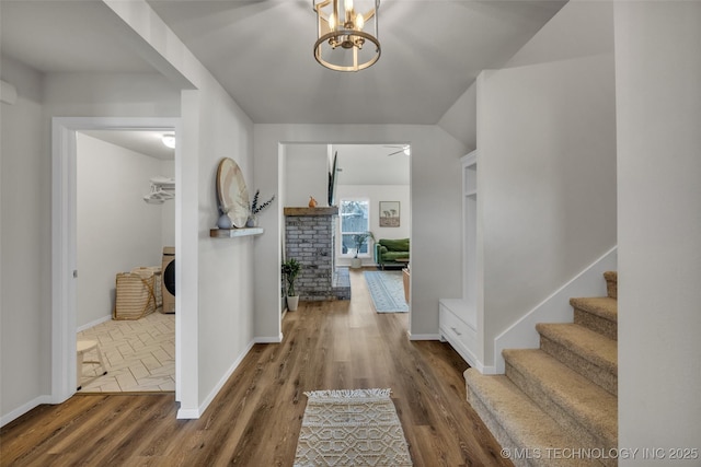 hall with a chandelier, wood-type flooring, and washer / dryer