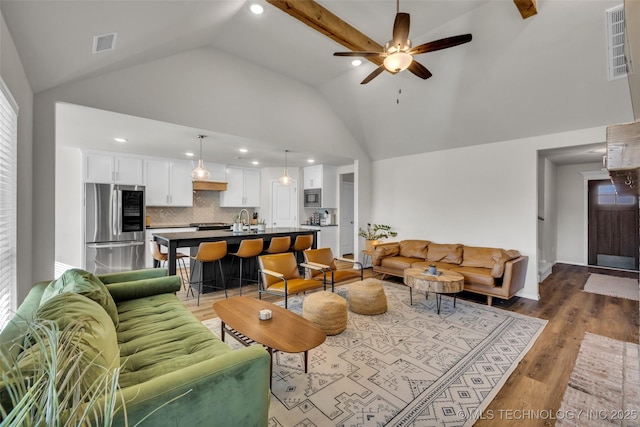 living room featuring vaulted ceiling with beams, ceiling fan, dark hardwood / wood-style flooring, and sink